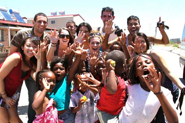 Group of students with children waving at the camera